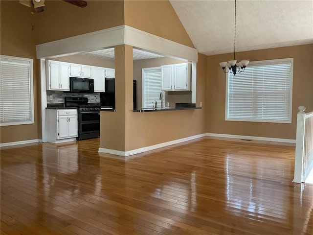 kitchen featuring black appliances, decorative light fixtures, wood-type flooring, and white cabinets