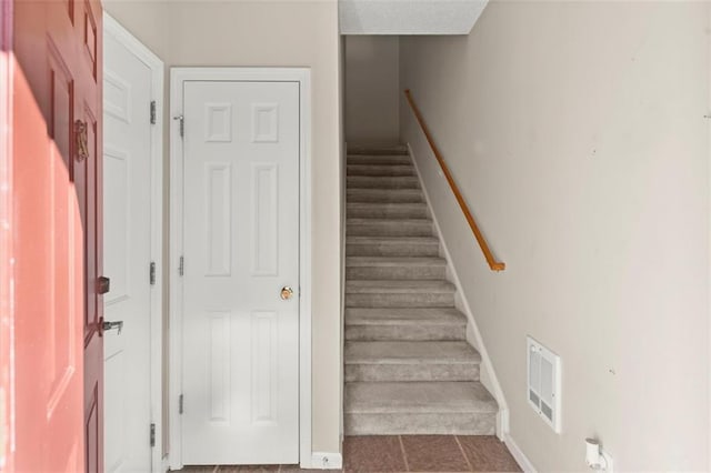 staircase featuring baseboards and visible vents