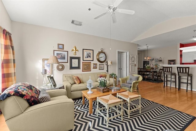 living area featuring vaulted ceiling, visible vents, a ceiling fan, and wood finished floors