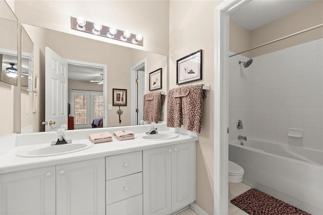 ensuite bathroom with double vanity, ceiling fan, and a sink