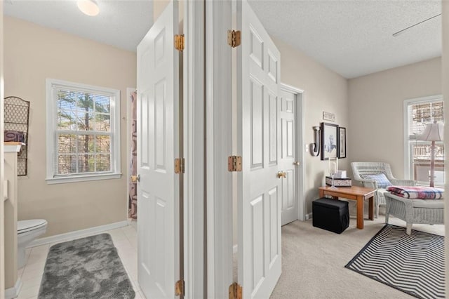 office area featuring light tile patterned floors, light colored carpet, baseboards, and a textured ceiling