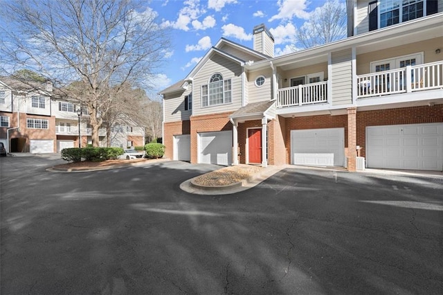 exterior space featuring brick siding, driveway, a chimney, and a garage