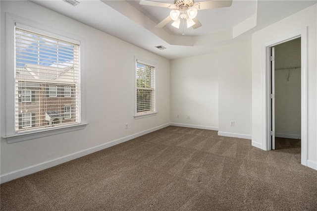 1935 Cobblestone Cir NE, Brookhaven, GA 30319 - unfurnished bedroom featuring carpet floors, a spacious closet, a tray ceiling, a ceiling fan, and a closet