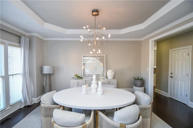 dining space featuring a chandelier, ornamental molding, dark wood-type flooring, and a tray ceiling