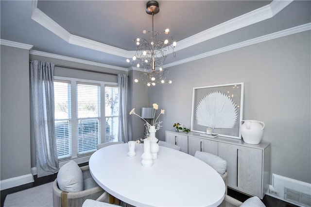 dining room with a raised ceiling, crown molding, and an inviting chandelier