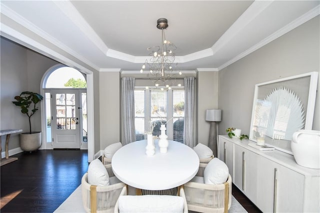 dining room with a chandelier, ornamental molding, a tray ceiling, and dark wood-type flooring