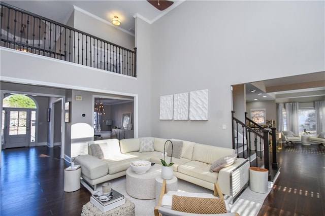 living room with dark hardwood / wood-style floors, a towering ceiling, ornamental molding, and a chandelier