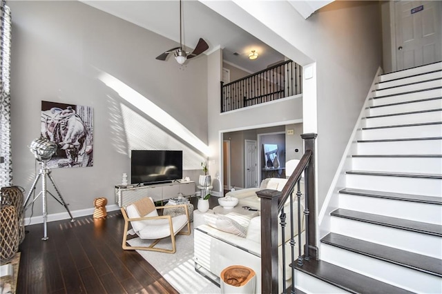 living room featuring ceiling fan, wood-type flooring, and a high ceiling