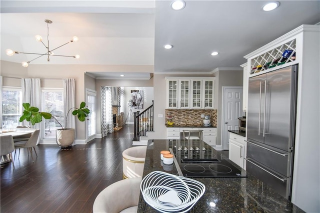 kitchen featuring white cabinets, hanging light fixtures, black electric cooktop, tasteful backsplash, and stainless steel built in refrigerator