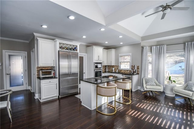 kitchen featuring tasteful backsplash, white cabinets, stainless steel appliances, and vaulted ceiling