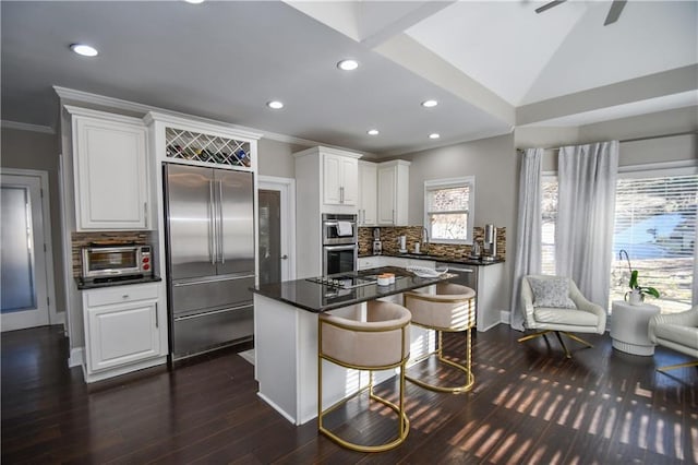 kitchen featuring a breakfast bar, a center island, white cabinets, tasteful backsplash, and stainless steel appliances