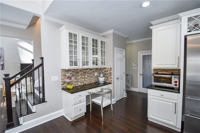 kitchen with backsplash, high quality fridge, crown molding, built in desk, and white cabinets