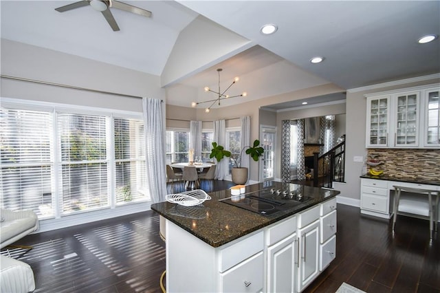 kitchen with a center island, dark wood-type flooring, vaulted ceiling, decorative backsplash, and white cabinets