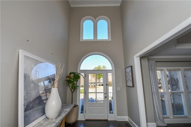 entrance foyer with dark hardwood / wood-style flooring, a towering ceiling, and crown molding