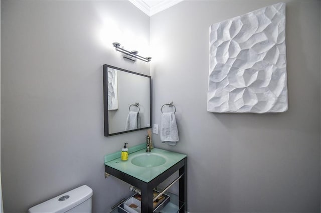 bathroom with toilet, ornamental molding, and sink