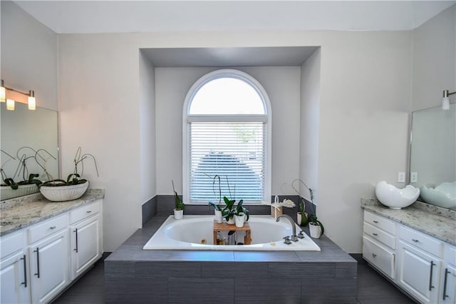 bathroom featuring tiled tub and vanity