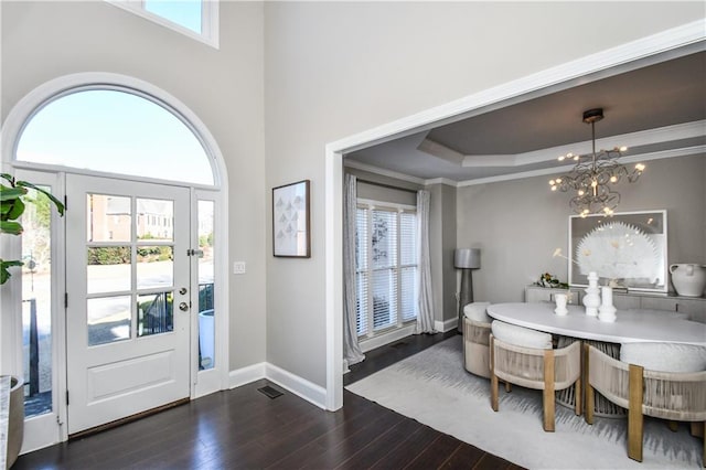 entryway with an inviting chandelier, ornamental molding, dark wood-type flooring, and a tray ceiling