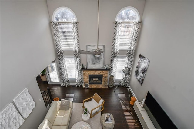 living room featuring a towering ceiling, a fireplace, and dark wood-type flooring