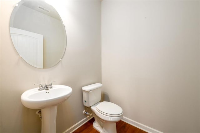 bathroom featuring toilet, visible vents, baseboards, and wood finished floors