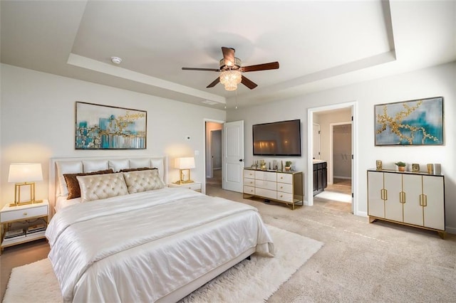 bedroom with a raised ceiling, light carpet, ceiling fan, and baseboards