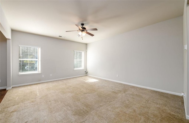 carpeted spare room with visible vents, ceiling fan, and baseboards