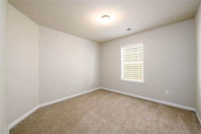 spare room featuring carpet floors, visible vents, and baseboards