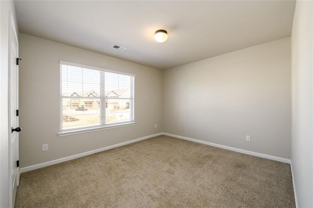 spare room featuring baseboards, visible vents, and carpet flooring