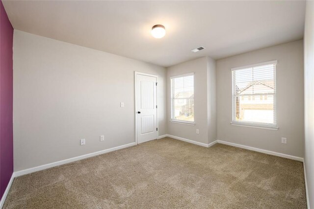 unfurnished room featuring carpet floors, visible vents, and baseboards