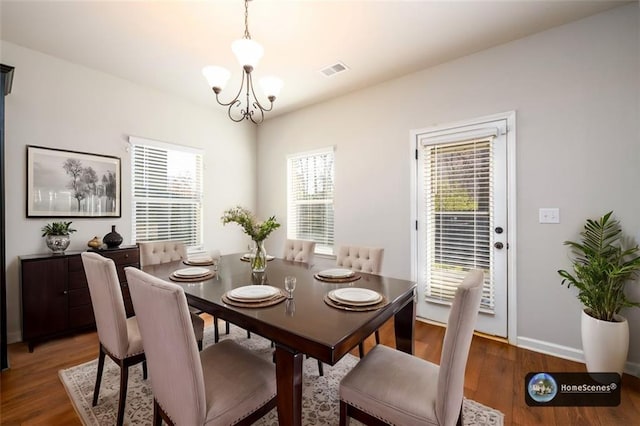 dining room featuring an inviting chandelier, baseboards, visible vents, and wood finished floors