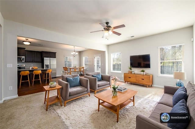 living room with light carpet, visible vents, baseboards, and ceiling fan with notable chandelier