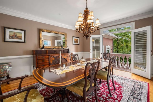 dining area featuring hardwood / wood-style floors, crown molding, and a chandelier