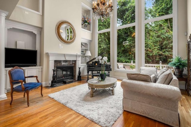 living room featuring a high end fireplace, wood-type flooring, a high ceiling, and a notable chandelier