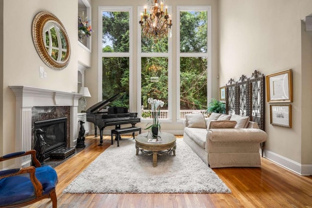 sitting room featuring a high end fireplace, light wood-type flooring, a wealth of natural light, and an inviting chandelier