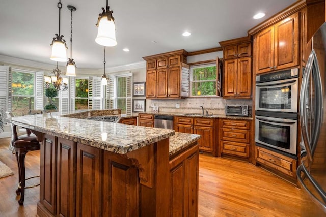 kitchen featuring light wood-type flooring, decorative light fixtures, and plenty of natural light