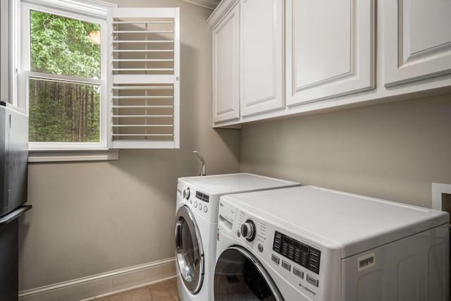 laundry area with washer and clothes dryer, light tile patterned flooring, and cabinets