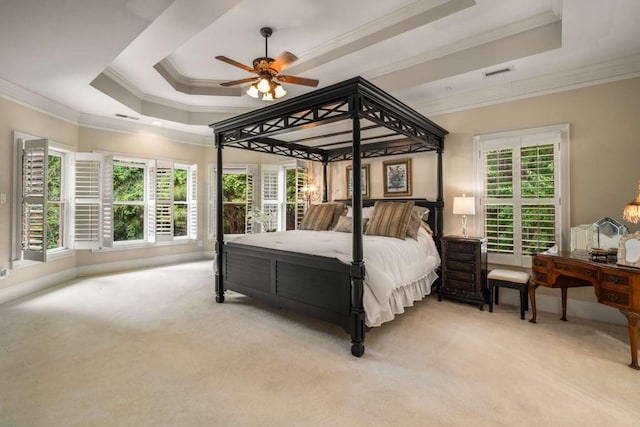 bedroom featuring a raised ceiling, multiple windows, ceiling fan, and light colored carpet