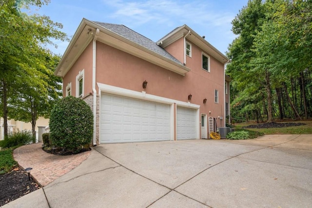 view of property exterior with cooling unit and a garage