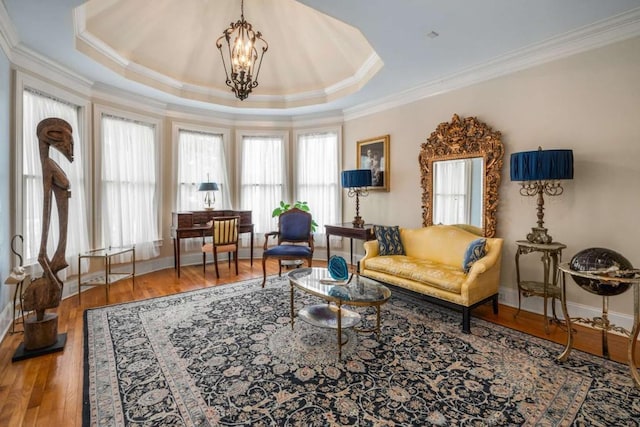 sitting room featuring hardwood / wood-style floors, a tray ceiling, ornamental molding, and a notable chandelier