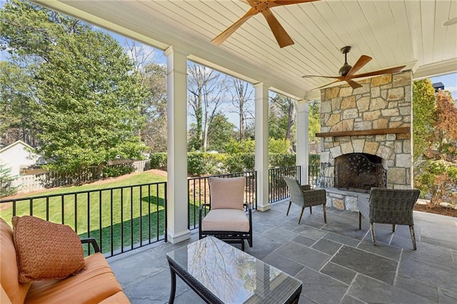 sunroom / solarium featuring wood ceiling, an outdoor stone fireplace, and a ceiling fan