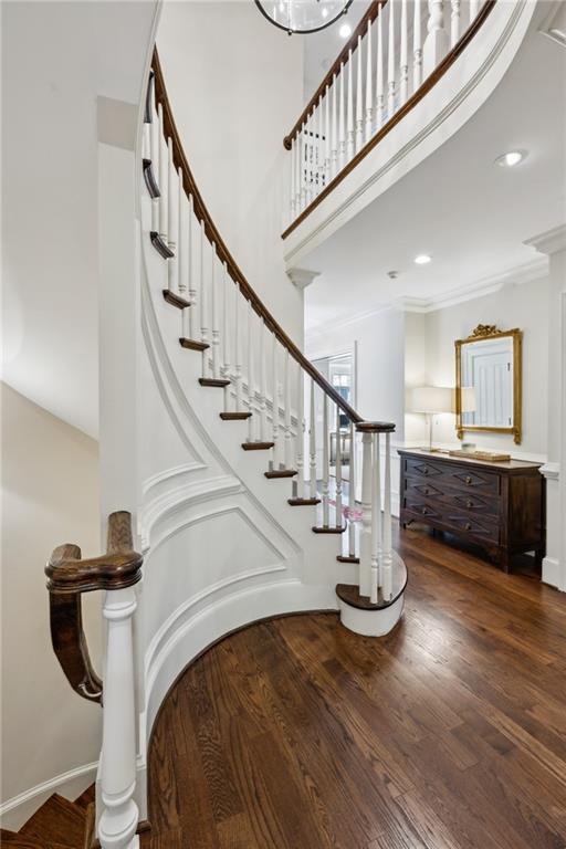 staircase featuring ornamental molding, wood finished floors, recessed lighting, a high ceiling, and baseboards