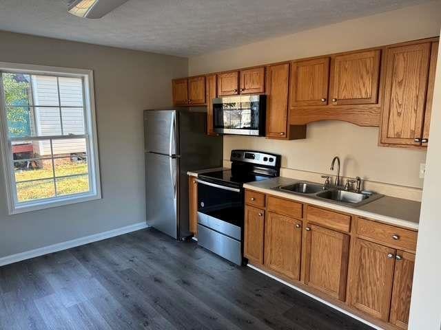 kitchen with dark wood-type flooring, appliances with stainless steel finishes, sink, and a textured ceiling