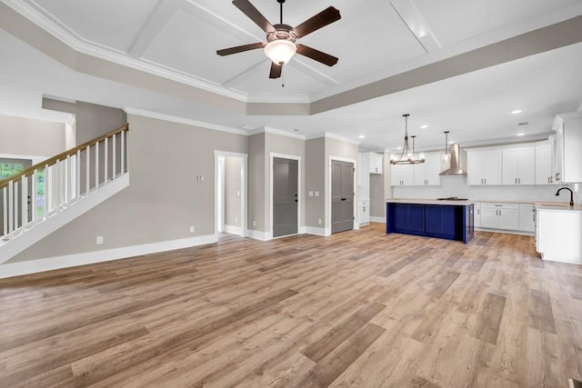 unfurnished living room featuring sink, ceiling fan with notable chandelier, light hardwood / wood-style floors, and ornamental molding