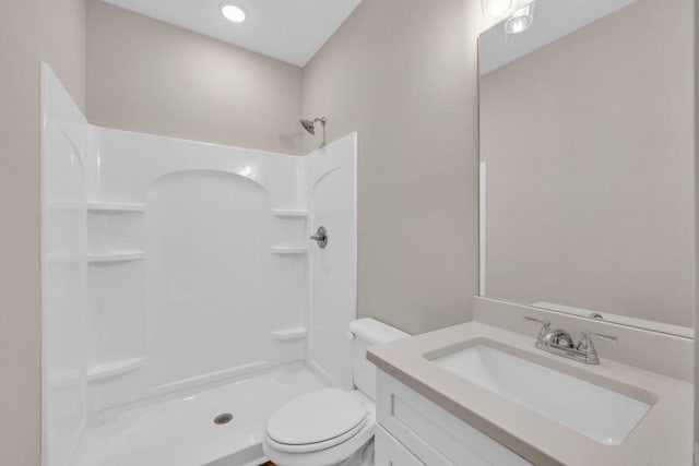 bathroom featuring vanity, walk in shower, and toilet