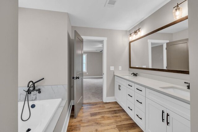 bathroom featuring hardwood / wood-style floors, a bath, and vanity