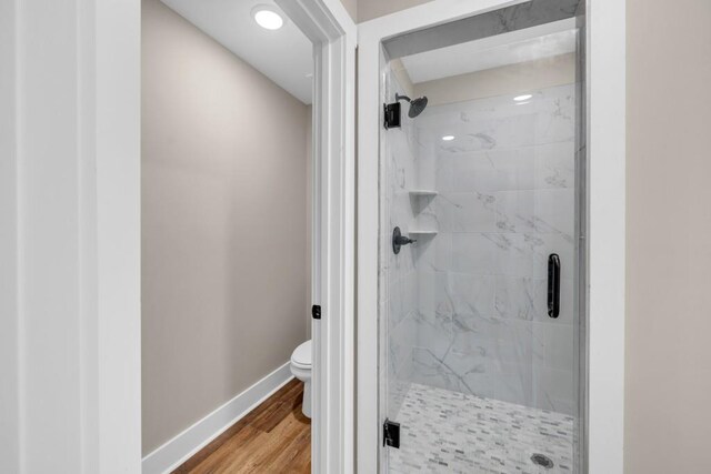 bathroom with toilet, hardwood / wood-style flooring, and walk in shower