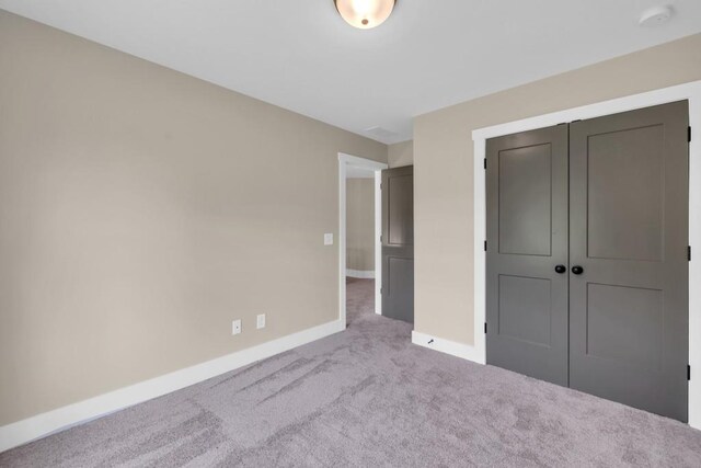 unfurnished bedroom featuring light carpet and a closet