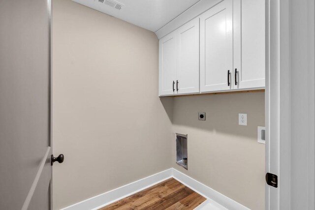 laundry area featuring hookup for an electric dryer, wood-type flooring, and cabinets