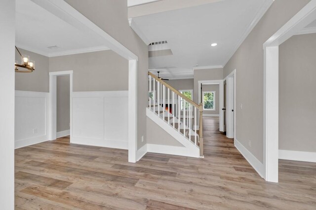 entrance foyer featuring crown molding, a chandelier, and light wood-type flooring