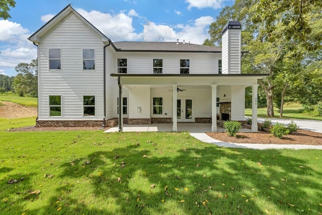 rear view of house featuring ceiling fan, a patio area, and a lawn