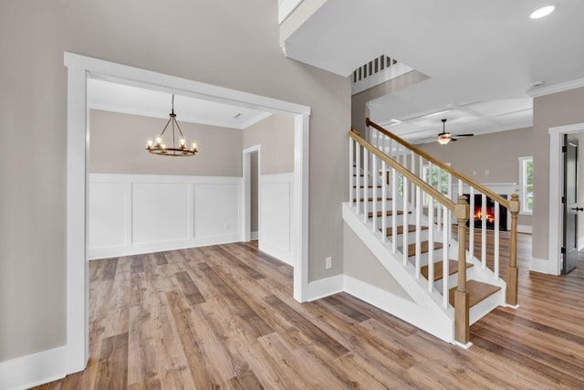 interior space featuring ceiling fan with notable chandelier, hardwood / wood-style flooring, and crown molding